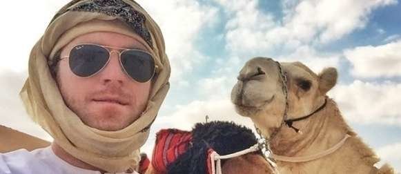 Max de Arabia junto a un camello en el desierto. 