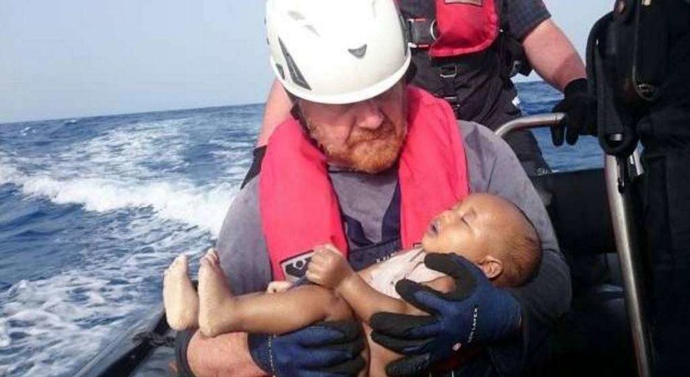 El bebé ahogado en el Mediterráneo es acunado por un voluntario alemán.