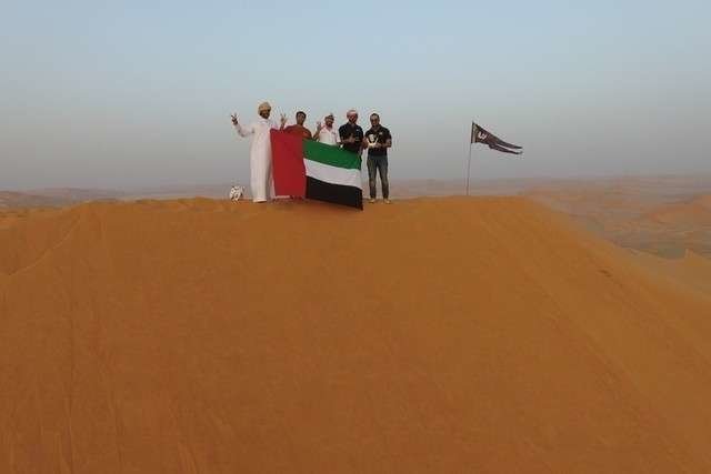Los miembros del Club Aventura EAU, tras colocar la bandera emiratí sobre la duna de Omán.