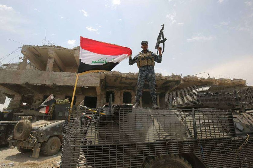 Un soldado iraquí iza una bandera en Mosul.