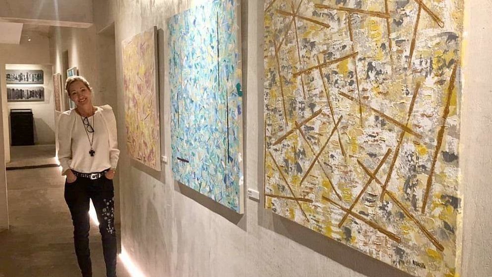 La pintora Paloma Redecilla, junto a algunas de sus obras en la exposición de Madrid. (Cedida)