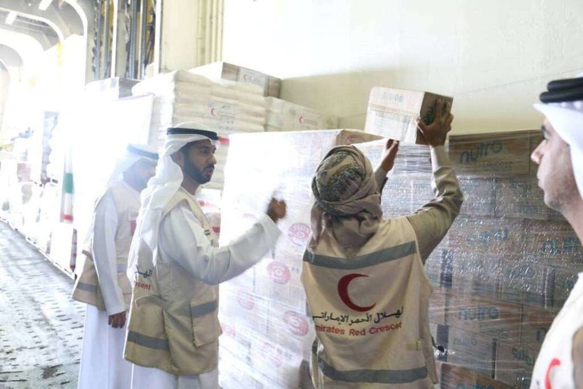 Miembros de la Media Luna Roja descargan la ayuda alimentaria en Yemen. (WAM)