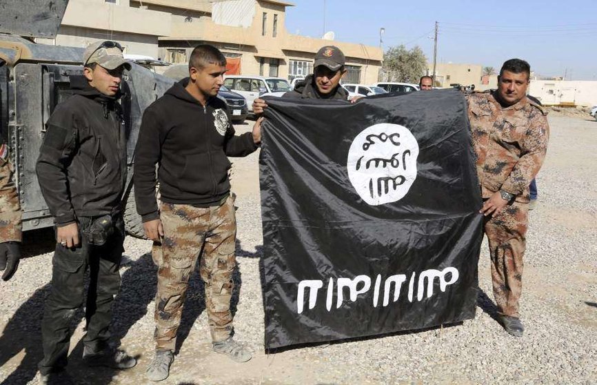 Soldados de las fuerzas especiales iraquíes sujetan una bandera del Daesh en la ciudad de Bartila, Irak. (Ahmed Jalil / EFE)