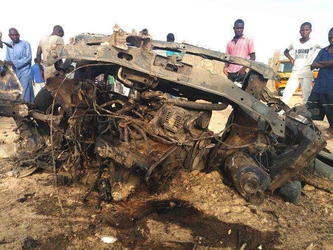 Varias personas observan un vehículo destruido durante el ataque de Boko Haram en Maiduguri este jueves.