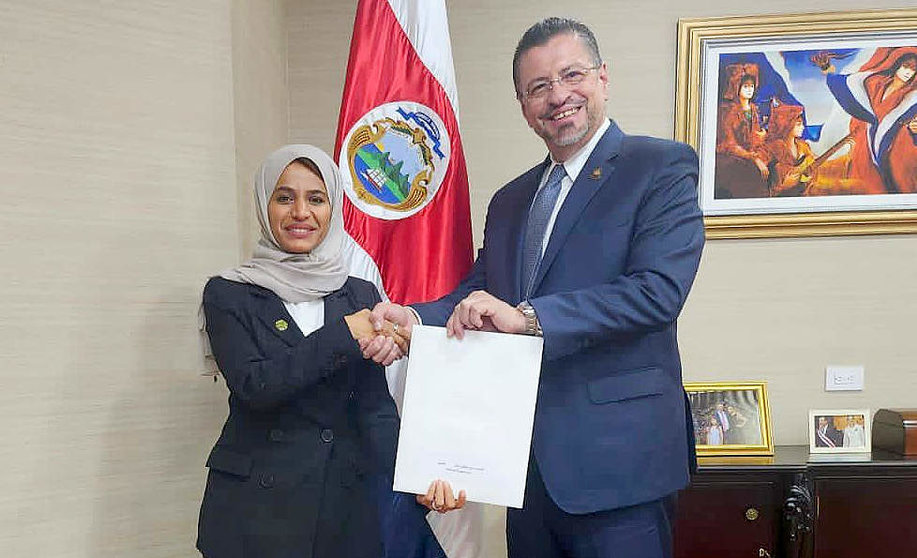 El presidente de Costa Rica recibe la invitación de manos de la embajadora emiratí Rawdha Alotaiba. (WAM)
