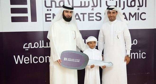 El afortunado ganador junto a su padre y el representante de la institución financiera.
