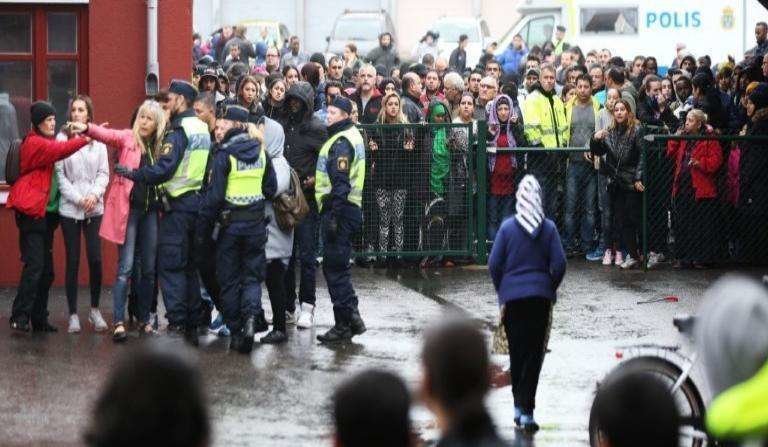 Oficiales de policía suecos brindan información a personas, mientras intentan asegurar el área exterior de la escuela. (AFP)