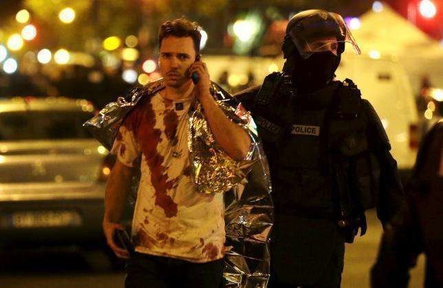 Un policía francés ayuda a una víctima cerca de la sala de concierto de Bataclan. (Reuters)