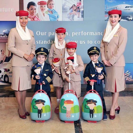 Personal de cabina y niños ataviados con el uniforme de Emirates Airline.