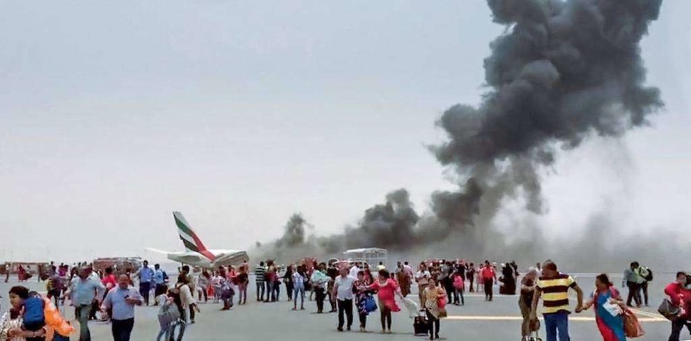 Pasajeros sobre la pista del aeropuerto de Dubai tras el desalojo del vuelo EK521.de Emirates.