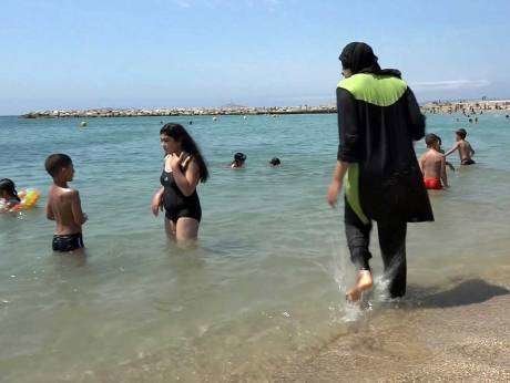 Una mujer porta un burkini en una playa.