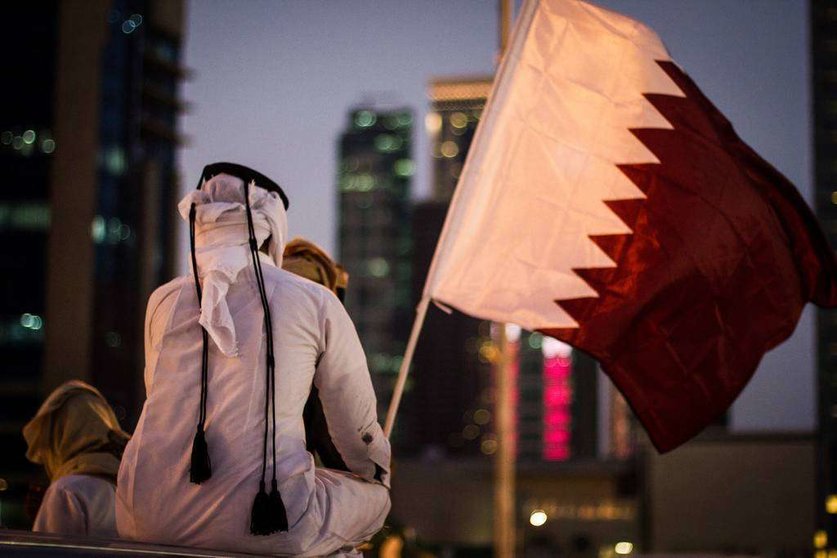 Un joven qatarí ante la bandera de su país.