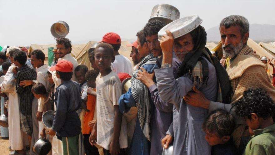 Yemeníes hacen cola para recibir alimentos de ayuda humanitaria.