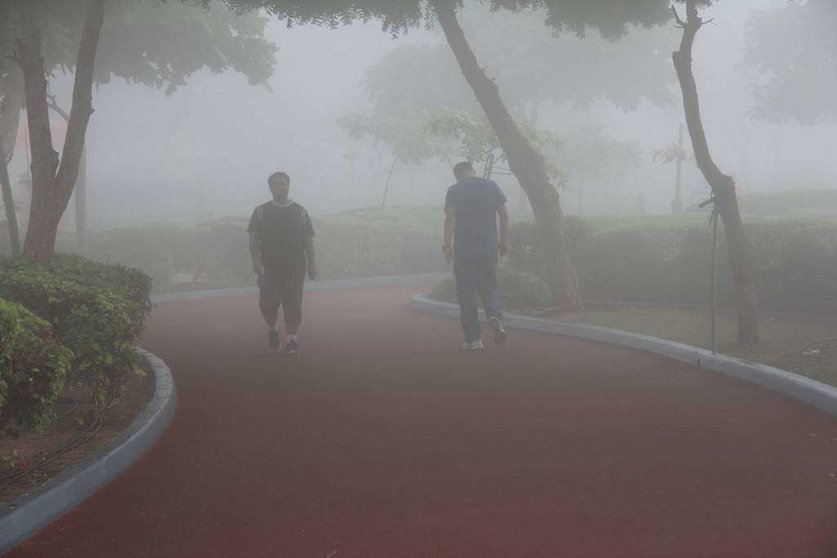 Residentes caminan entre la niebla por el paseo marítimo de la Corniche de Ras Al Khaimah. (R. Pérez)