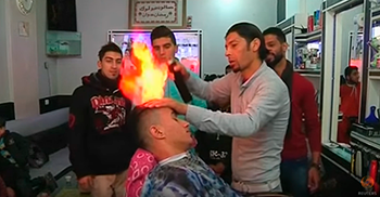 El barbero Ramadán Odwan aplica el tratamiento con fuego a uno de sus clientes.