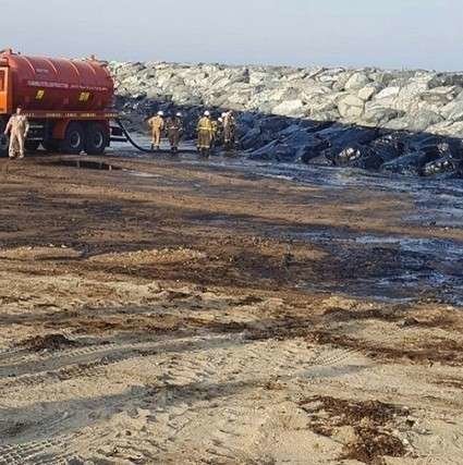 Trabajadores en Sharjah limpian la playa tras el vertido de petróleo.