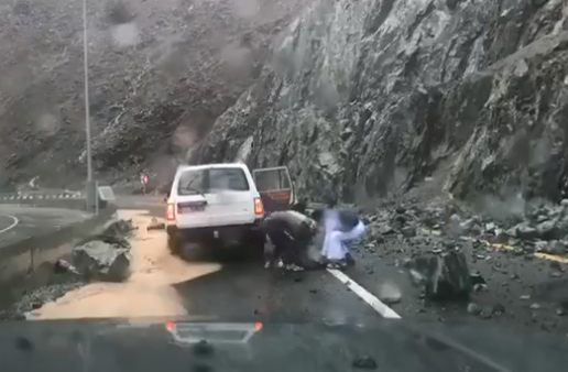 Varias personas retiran una roca desprendida sobre la carretera en Kalba Sweet Valley. (Ahmed al Badwawi, NCM)