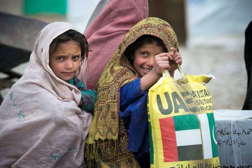 Una niña con un saco de ayuda alimentaria emiratí. (WAM)