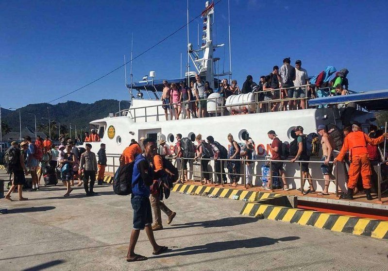 Los lugareños y turistas extranjeros  evacuados de las islas Gili desembarcanen el puerto de Bangsal, Lombok.