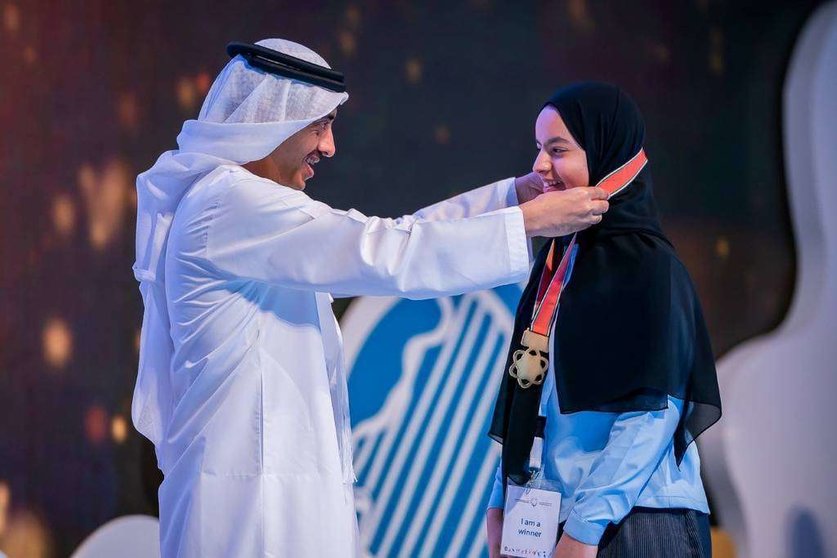 El ministro Abdullah bin Zayed Al Nahyan coloca una medalla a una de las alumnas homenajeadas. (WAM)