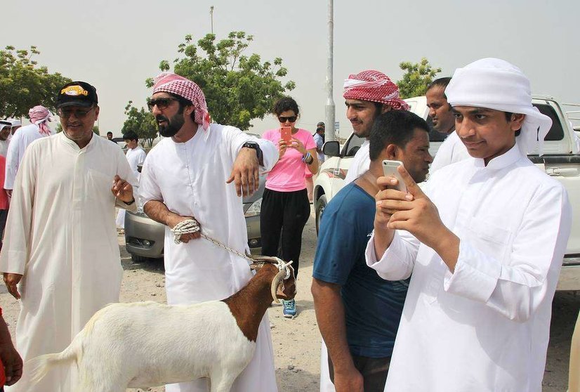 Un joven emiratí realiza una foto con su celular a una reunión en el mercado de corderos de Ras Al Khaimah. (EL CORREO)