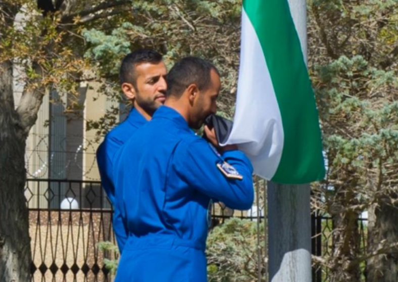 Astronautas emiratíes besan la bandera de su país durante la ceremonia de izado. (WAM)