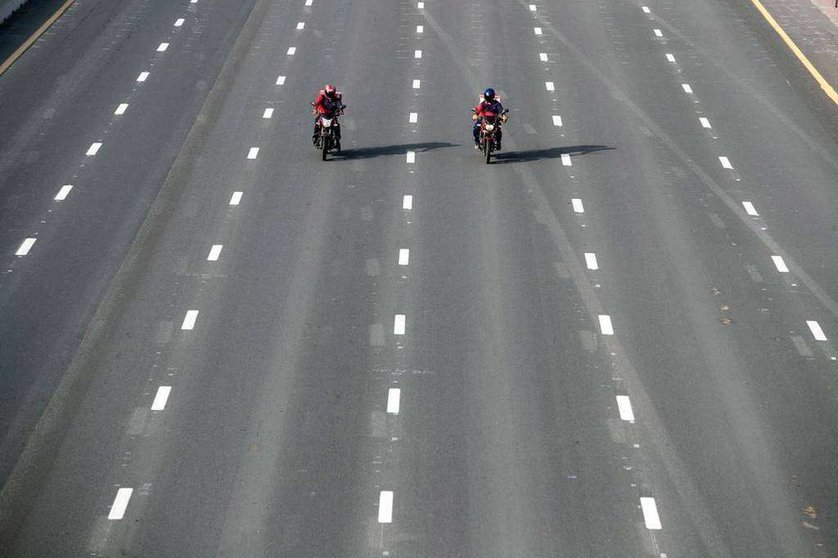 Dos repartidores en una calle vacía de Dubai. (EPA)