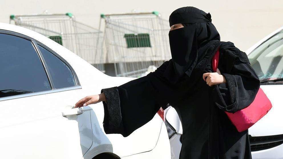 En la imagen de AFP, una mujer saudí a punto de abrir la puerta de un coche.