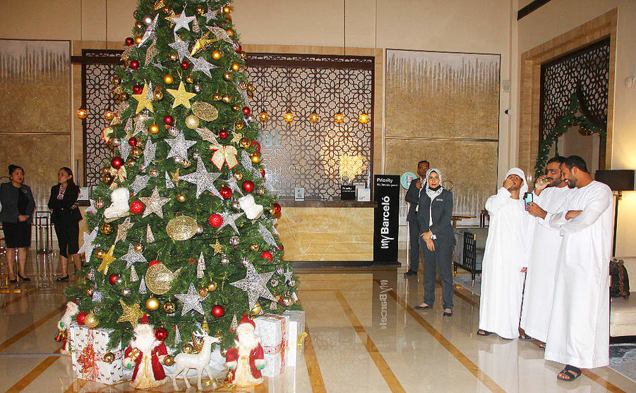 Varios árabes observan el árbol de Navidad en el hotel Occidental Al Jaddaf. (EL CORREO)