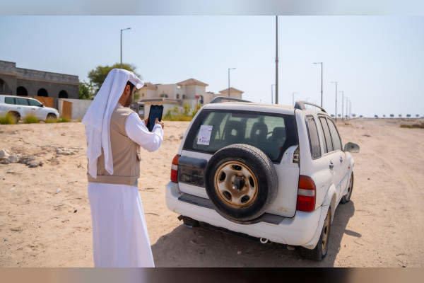 Un funcionario fotografía un coche abandonado en el emirato de Abu Dhabi. (WAM)