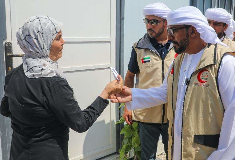 Un funcionario emiratí entrega la llave de una vivienda a una mujer siria. (WAM)