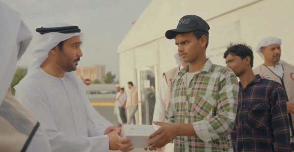 Un funcionario del Ministerio de Recursos Humanos y Emiratización entrega una caja con alimentos a un trabajador. (MoHRE)